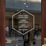 Custom open hours decal applied on wooden glass door, business storefront vinyl lettering, personalized store hours sticker by TheRetractableBanner.Shop