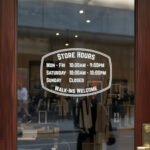 Custom open hours decal applied on wooden glass door, business storefront vinyl lettering, personalized store hours sticker by TheRetractableBanner.Shop