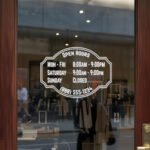 Custom open hours decal applied on wooden glass door, business storefront vinyl lettering, personalized store hours sticker by TheRetractableBanner.Shop
