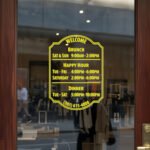 Custom open hours decal applied on wooden glass door, business storefront vinyl lettering, personalized store hours sticker by TheRetractableBanner.Shop