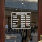 Custom open hours decal applied on wooden glass door, business storefront vinyl lettering, personalized store hours sticker by TheRetractableBanner.Shop
