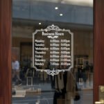 Custom open hours decal applied on wooden glass door, business storefront vinyl lettering, personalized store hours sticker by TheRetractableBanner.Shop