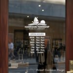 Custom open hours decal applied on wooden glass door, business storefront vinyl lettering, personalized store hours sticker by TheRetractableBanner.Shop