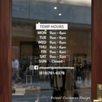 Custom open hours decal applied on wooden glass door, business storefront vinyl lettering, personalized store hours sticker by TheRetractableBanner.Shop