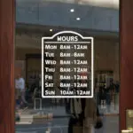 Custom open hours decal applied on wooden glass door, business storefront vinyl lettering, personalized store hours sticker by TheRetractableBanner.Shop