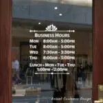 Custom open hours decal applied on wooden glass door, business storefront vinyl lettering, personalized store hours sticker by TheRetractableBanner.Shop