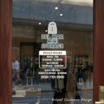 Custom open hours decal applied on wooden glass door, business storefront vinyl lettering, personalized store hours sticker by TheRetractableBanner.Shop
